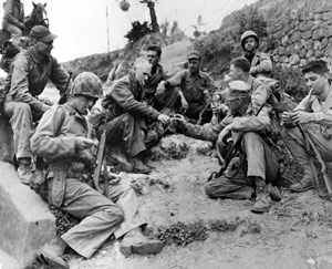 Ernie Pyle passes a lighter sitting in a group of soldiers.