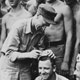 Ernie Pyle signs his autograph atop a soldier's head.