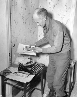Ernie Pyle hovers near his typewriter.
