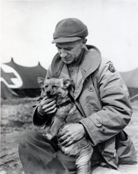 Ernie Pyle sits holding a small dog.