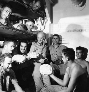 Ernie Pyle stands joking with a group of soldiers.