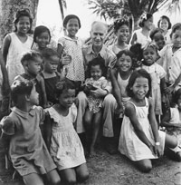 Ernie Pyle stands with a group of children.